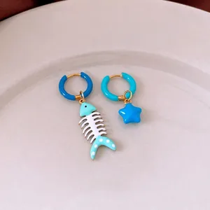 Asymmetric gold titanium steel hoop earrings with blue enamel fish bone and star charms