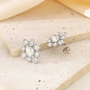 Detailed view of silver flower earrings with crystals on a stone plate and silk background