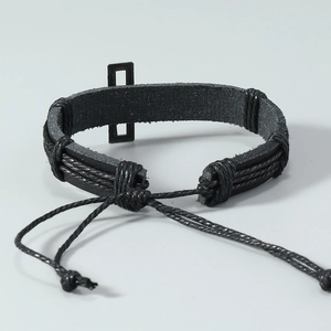 Detail of hand-woven black leather bracelet with rectangular metal plate and drawstring