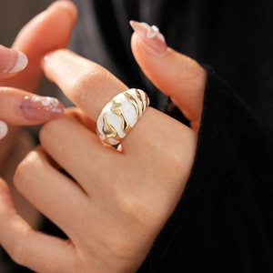 Detail of wide vintage gold ring with white enamel wave patterns worn on a finger