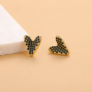 Detailed close-up of heart-shaped gold stud earrings with dark green micro-pave crystals