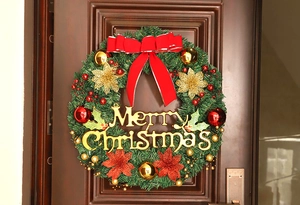 Close-up of a 40cm Christmas wreath with red bows and gold ornaments on a dark wood door