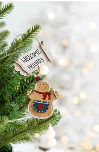 Christmas gingerbread man welcome door sign hanging on a festive tree branch with soft bokeh