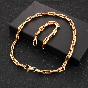 Detailed view of golden coffee bean link chain set with lobster clasp on a gift box