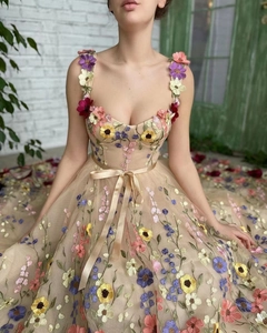 Détail de robe en tulle champagne avec broderies florales 3D colorées et nœud en satin