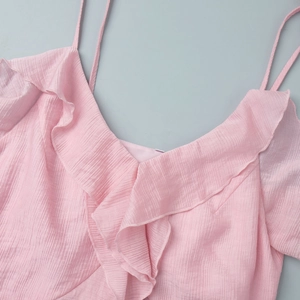 Detail of pink ruffled V-neck top with fine plissé texture and thin double straps
