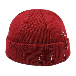 Close-up of red miki hat featuring silver metal rings, safety pin, and distressed knit detail