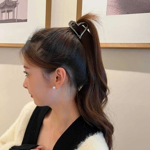 Elegant metallic heart-shaped hair claw clip in dark silver finish worn on high ponytail