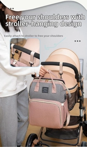 Detail of multi-functional pink and grey diaper bag hanging on a baby stroller handle