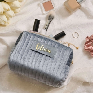 Macro detail of a grey velvet cosmetic bag with gold zipper and custom Olivia text
