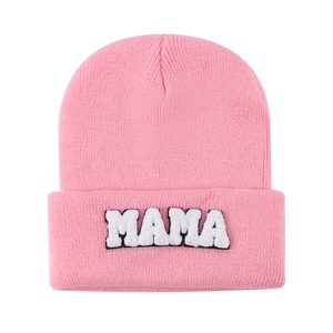Detailed view of pink knitted beanie featuring white MAMA chenille letter embroidery