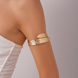 Detail of vintage gold upper arm cuff with intricate embossed vine patterns on model