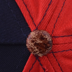 Gros plan sur le bouton du haut d'une casquette de baseball bicolore rouge et bleu marine