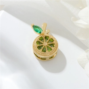Macro view of 14k gold-plated orange pendant with green crystals on white floral lace