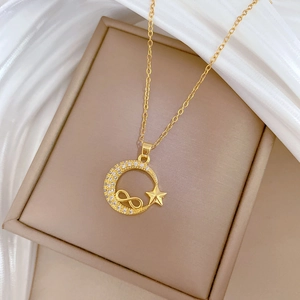 Detail of gold star and moon crescent pendant with crystal pavé on a beige jewelry box