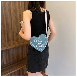 Détail d'un sac bandoulière en forme de cœur bleu et rose avec broderie élégante