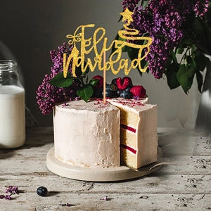 Golden glitter Christmas tree cake topper with Feliz Navidad text on a festive cake