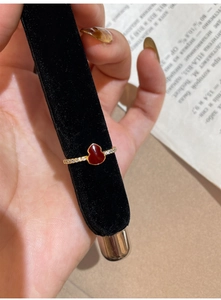 Détail d'une bague gourde en forme de cœur rouge doré ornée de pierres de zircon brillantes