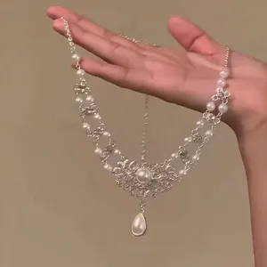 Détail du collier en dentelle argentée avec perles blanches et pendentif goutte