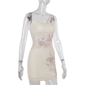 Détail des motifs floraux en strass roses sur l'ensemble haut et jupe moulante crème