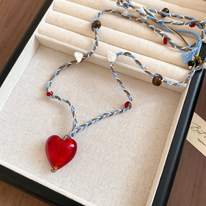 Dettaglio del ciondolo a cuore rosso con cordino intrecciato boho e perline di legno