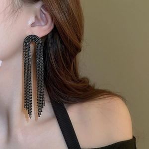 Close-up of model wearing black rhinestone tassel earrings with U-shaped design