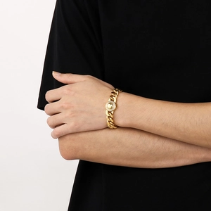 Detail of 11mm gold-tone Cuban link bracelet with iced-out circular charm on male model
