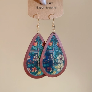 Detailed view of teardrop earrings with floral print and wood-style borders