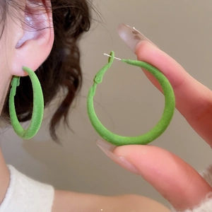 Détail de la boucle d'oreille créole verte floquée montrant texture et épaisseur