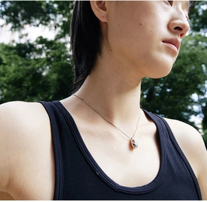 Detailaufnahme eines silbernen Bohnen-Anhängers mit Diamant an einer Schlangenkette