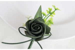 Detail of dark green PE foam rose boutonniere with delicate silk ribbon and green leaves