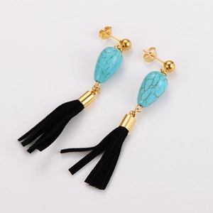 Détail de boucles d'oreilles vintage dorées avec pierres turquoise et pompons noirs en tissu