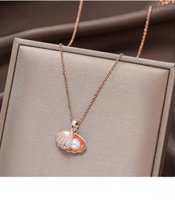 Detail of 18k rose gold shell pendant with shimmering diamonds and a white pearl insert