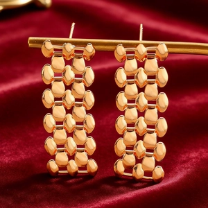 Detailed close-up of golden scale mesh drop earrings on a luxury velvet backdrop