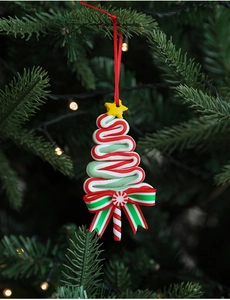 Detail of red, green and white wavy Christmas tree ornament on a pine branch with bokeh lights