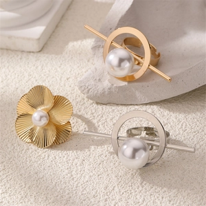 Detailed shot of gold floral pearl ring and geometric metal rings on stone display