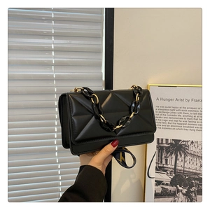 Chic black quilted crossbody bag with bold chain and wide lettered strap for urban fashion