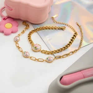 Detail of vintage gold pearl bracelets with floral enamel charms and metal chain links