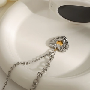 Elegant heart-shaped stainless steel necklace with textured silver pendant and gold center