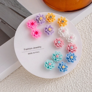 Set of colorful floral titanium steel stud earrings on a white circular display card