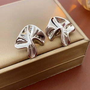 Close-up of silver stud earrings with an abstract wrinkled design on a jewelry box