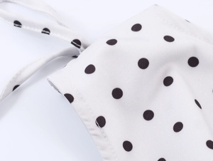 Close-up of retro white fabric with black polka dots and detailed stitching textures