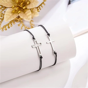 Détail de bracelets tressés noirs avec pendentifs croix en argent évidés et pleins