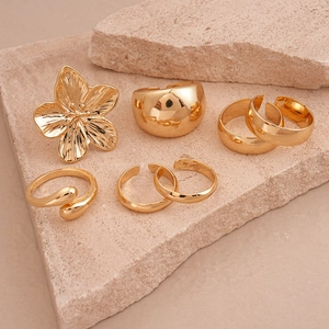 Detailed macro view of 6-piece gold-plated ring set on stone with floral and geometric designs