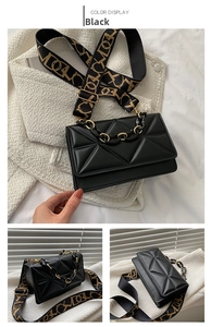Detail view of black crossbody bag with geometric texture and patterned wide strap