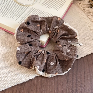 Brown polka dot scrunchie with white lace edges on a vintage background