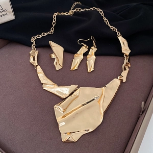 Macro view of golden jewelry set with irregular geometric textured folds and liquid metal finish