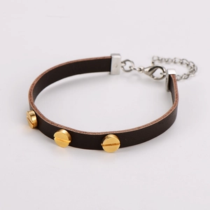 Dettaglio di un bracciale in pelle marrone scuro con rivetti a vite dorati e chiusura