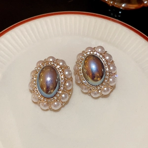 Macro detail of vintage oval earrings with central dark gem and pearl halo accents