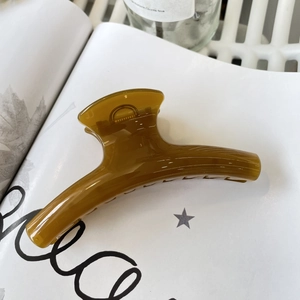 Detail of a large amber brown resin hair claw clip resting on a white book page